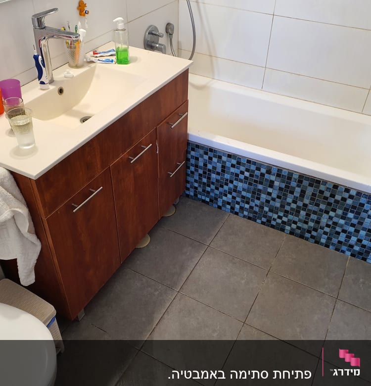 כיור אמבטיה עם ברז, ארון ומגבת תלויה